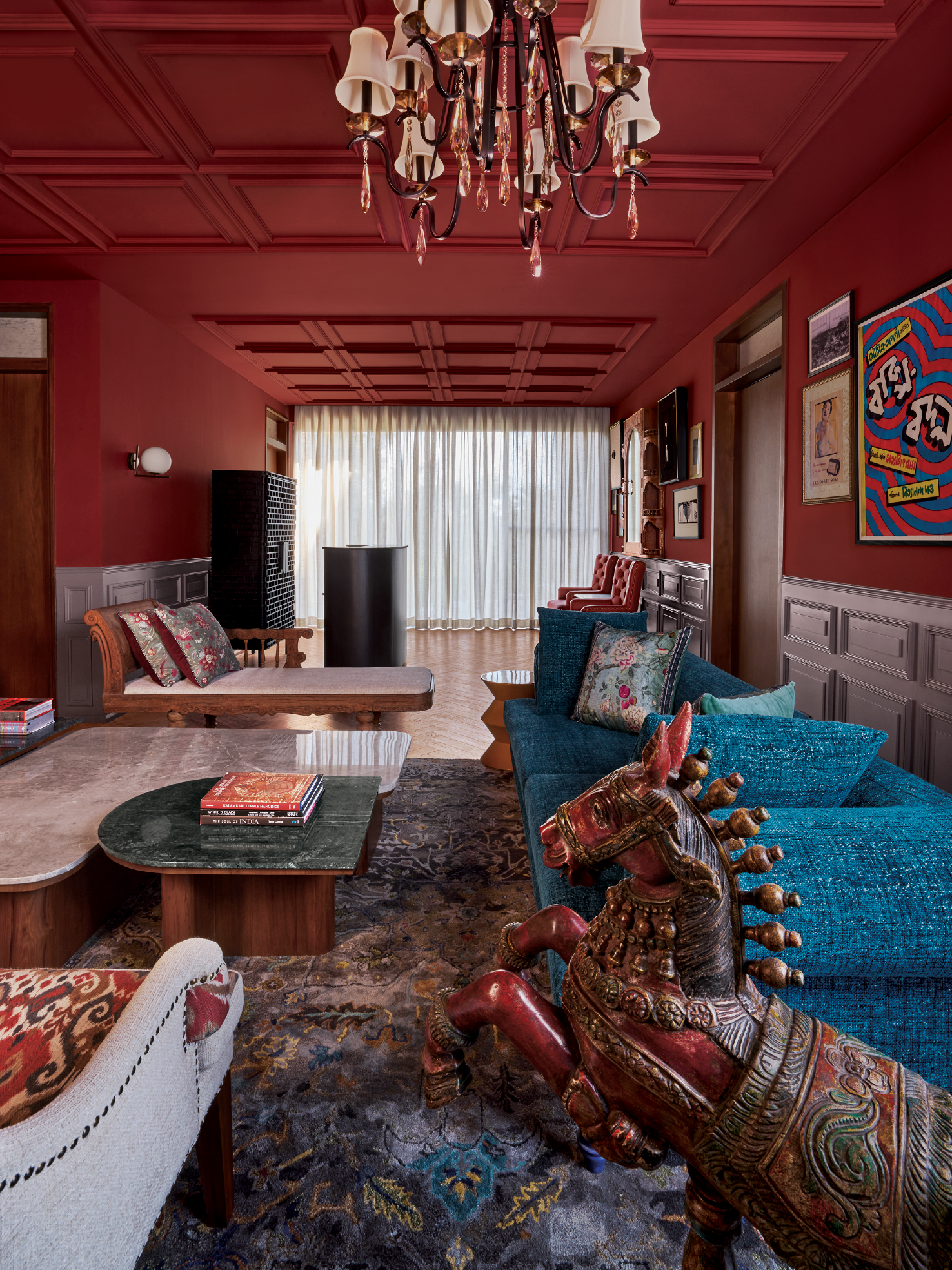 Richly coloured living room with deep red coffered ceiling and brass chandelier in Abin Design Studio home